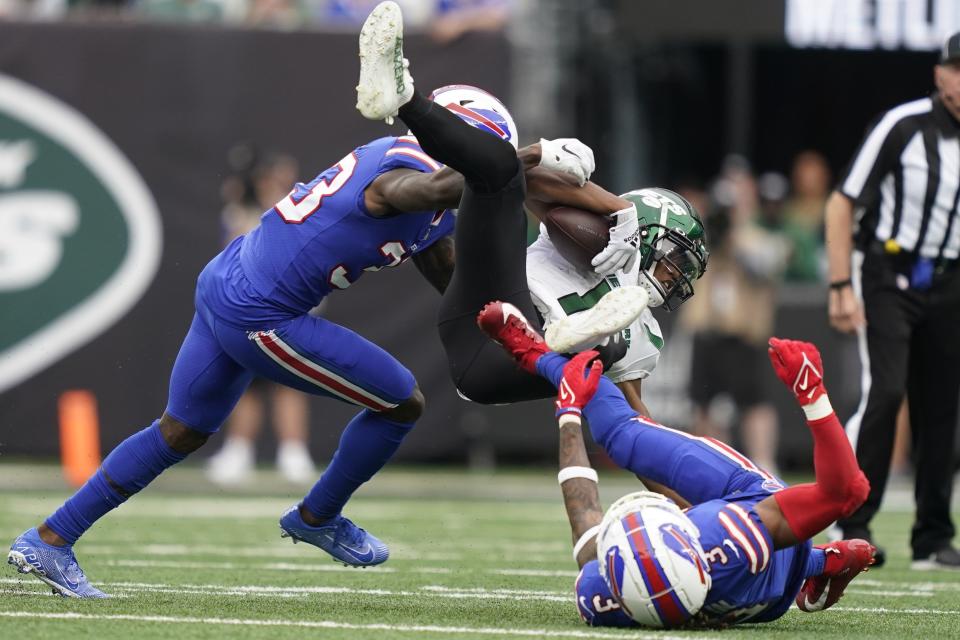 New York Jets' Garrett Wilson, center, dives over Buffalo Bills' Damar Hamlin (3) as Bills' Siran Neal (33) closes in during the first half of an NFL football game, Sunday, Nov. 6, 2022, in East Rutherford, N.J. (AP Photo/John Minchillo)