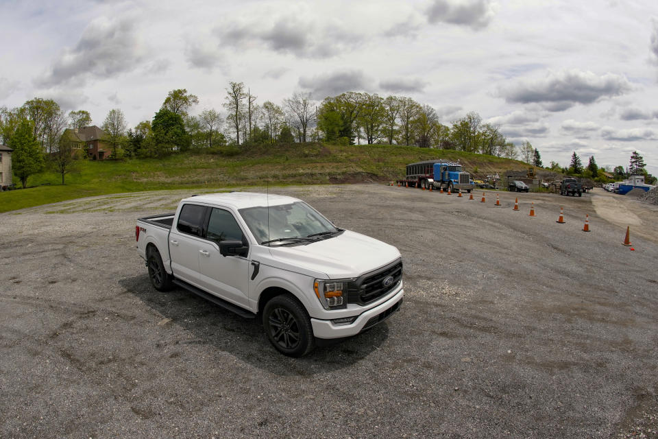 In this photo made on Thursday, May 6, 2021, a salesman from the Shults Ford dealership in Wexford, Pa. sits in one of the Ford F150 trucks at their nearby empty pickup truck inventory storage lot. Ford is warning that it expects to make only half the normal number of vehicles from now through June. Bazzy normally stocks 400-500 pickup trucks at his three Ford dealers, but is down around 100. He's confident that he can keep customers happy if they can order a truck and get it in four weeks, but he fears losing business to competing brands with a huge stock. (AP Photo/Keith Srakocic)