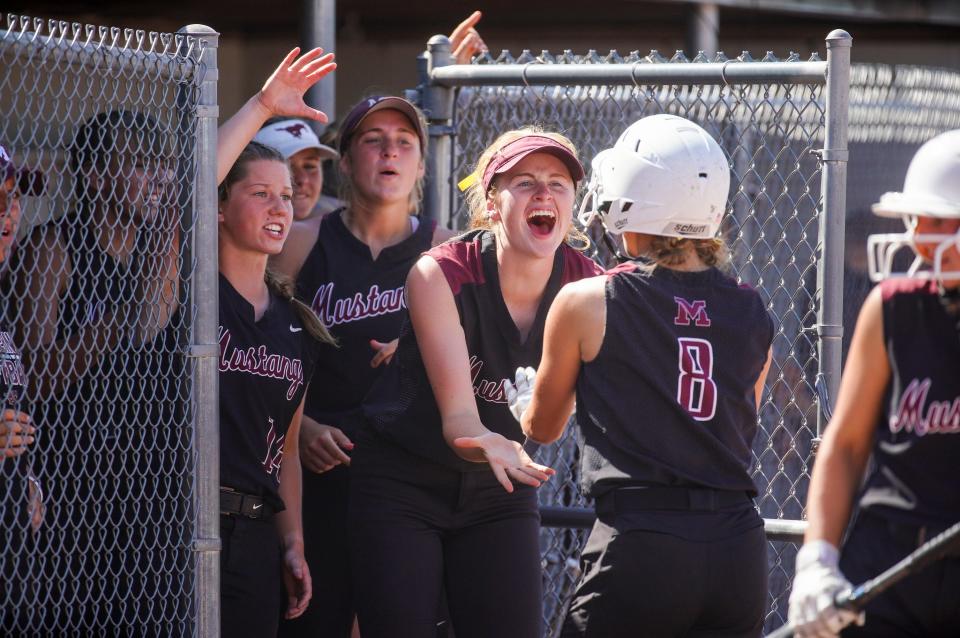 Mount Vernon's Elsa Appleton (8) is greeted by teammates in the dugout after scoring a run against Assumption during the Class 3A softball state championship on Friday at the Harlan Rogers Sports Complex in Fort Dodge.