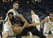Detroit Pistons' Andre Drummond (0) is fouled as he drives between Milwaukee Bucks' Brook Lopez and George Hill during the first half of Game 1 of an NBA basketball first-round playoff series Sunday, April 14, 2019, in Milwaukee. (AP Photo/Aaron Gash)
