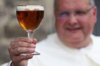 Norbertine Father Karel poses with a Grimbergen beer, symbolised by a phoenix, in the courtyard of the Belgian Abbey of Grimbergen before announcing that the monks will return to brewing after a break of two centuries, in Grimbergen, Belgium May 21, 2019. REUTERS/Yves Herman