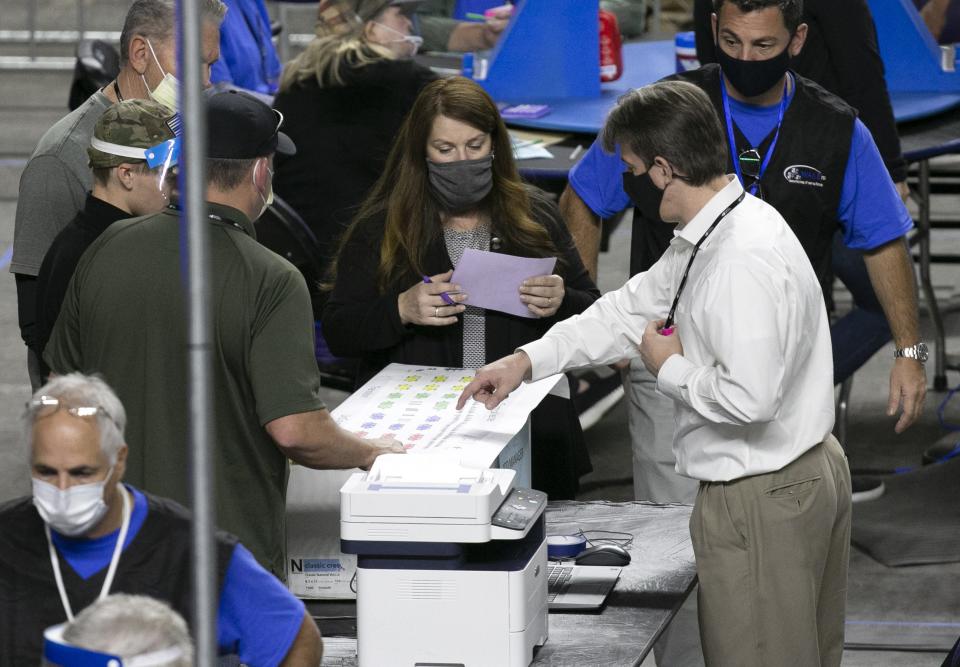Cyber Ninjas CEO Doug Logan (right) talks with others on  the coliseum floor as Maricopa County ballots from the 2020 general election are examined and recounted by contractors hired by the Arizona Senate in an audit at the Veterans Memorial Coliseum in Phoenix on May 24, 2021. Cyber Ninjas is the contracting firm hired to handle the audit.