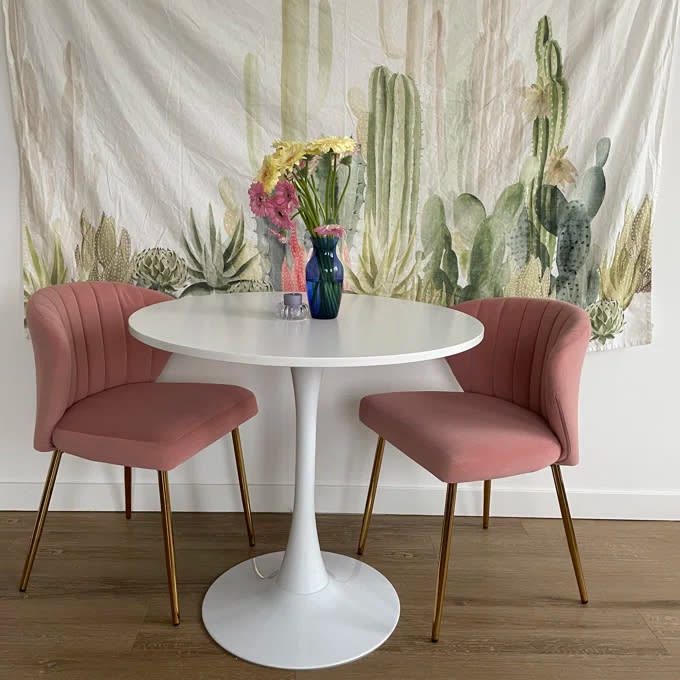 two pink tufted velvet chairs on either side of a white circular table