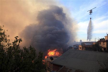 A helicopter assists in fighting a fire at the location where a forest fire burned several neighbourhoods in the hills in Valparaiso city, northwest of Santiago, April 13, 2014. REUTERS/Cristobal Saavedra