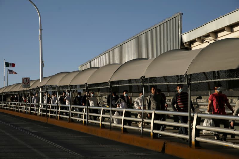 Mexican immigrants walk across the Paso del Norte border bridge after being deported from the United States amid the spread of the coronavirus disease (COVID-19), in Ciudad Juarez