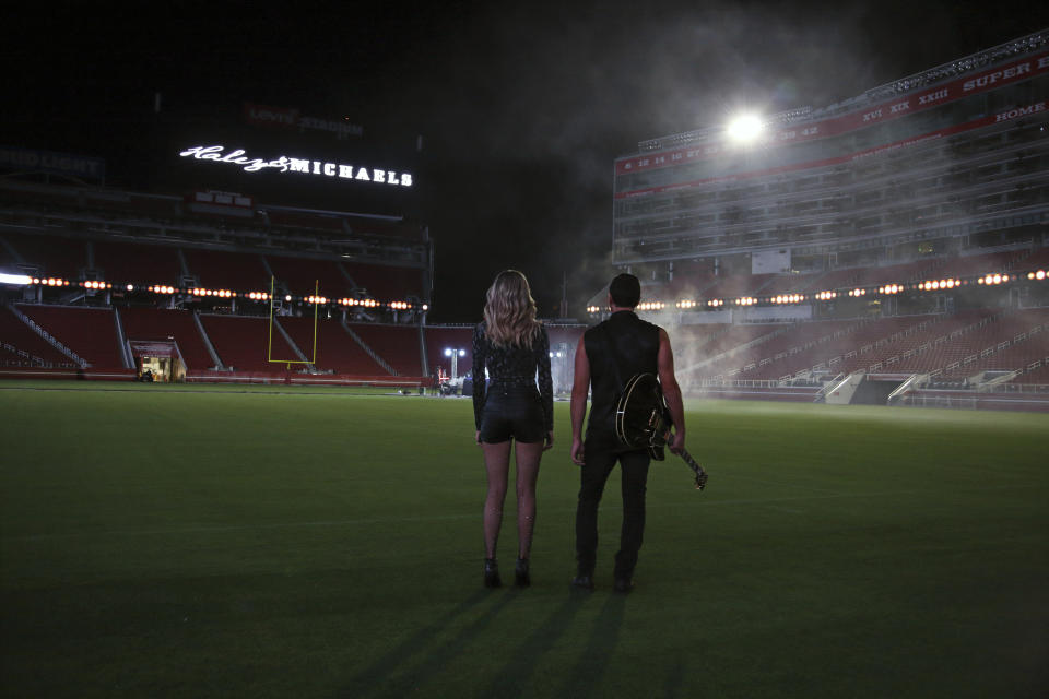 This July 25, 2019, photo provided by Jon-Paul Bruno shows Shannon Haley and Ryan Michaels during the shooting of a music video at Levi’s Stadium in Santa Clara, Calif. NFL players’ dreams usually center on scoring touchdowns and making game-saving tackles. Then they watch videos of their performances. It’s not that much different for musicians, particularly the husband/wife country duo of Shannon Haley and Ryan Michaels. Their big play occurred in Levi’s Stadium, home of their longtime favorite team, the 49ers. (Jon-Paul Bruno via AP)