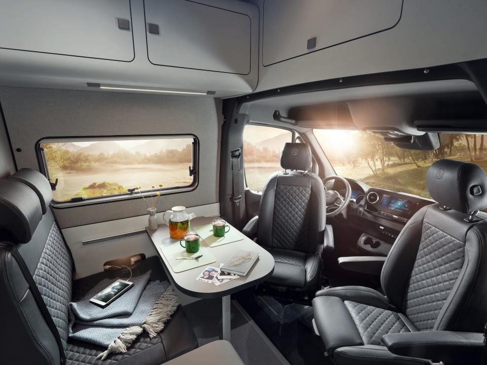 A dining table in a camper van. The driver and passenger seats have swiveled to face the table.