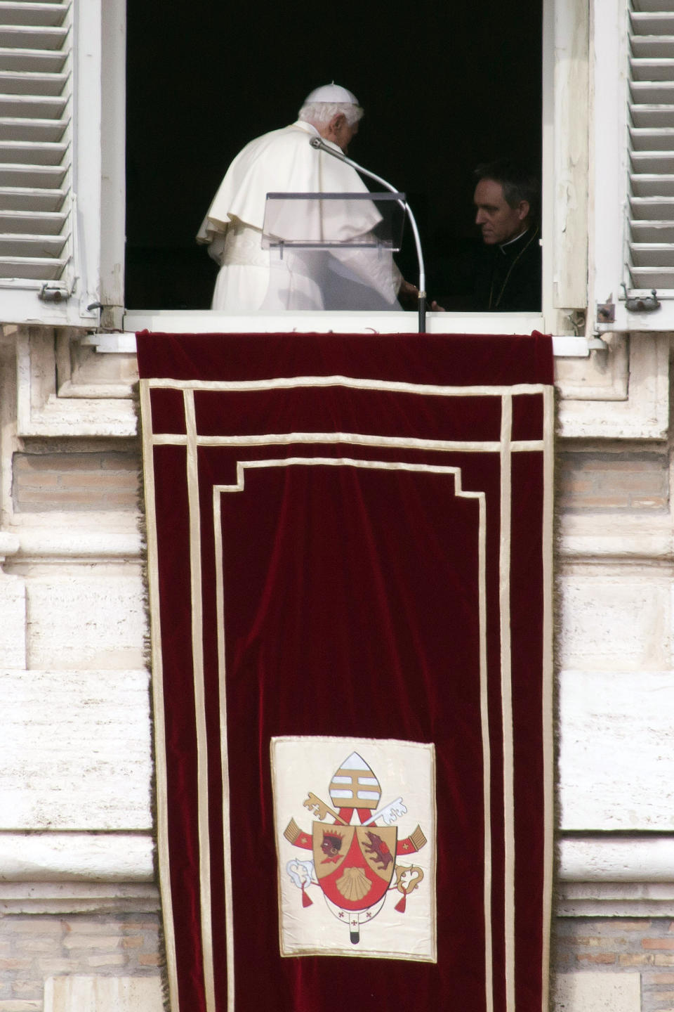 FILE - Pope Benedict XVI, flanked by his personal secretary Archbishop Georg Gaenswein, as he turns away from a window overlooking St. Peter's Square after delivering his last Angelus noon prayer, at the Vatican, on Feb. 24, 2013. He was the reluctant pope, a shy bookworm who preferred solitary walks in the Alps and Mozart piano concertos to the public glare and majesty of Vatican pageantry. When Cardinal Joseph Ratzinger became Pope Benedict XVI and was thrust into the footsteps of his beloved and charismatic predecessor, he said he felt a guillotine had come down on him. The Vatican announced Saturday Dec. 31, 2022 that Benedict, the former Joseph Ratzinger, had died at age 95. (AP Photo/Andrew Medichini, File)