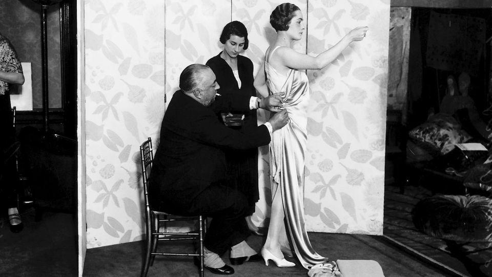 Designer Paul Poiret, pictured draping a bias-cut silk gown onto a fit model. - Mirrorpix/Getty Images