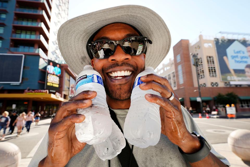 Jody Thompson sells cold water to the fans in the 119 degree heat arriving for the Morgan Wallen concert at Chase Field in Phoenix on July 19, 2023.