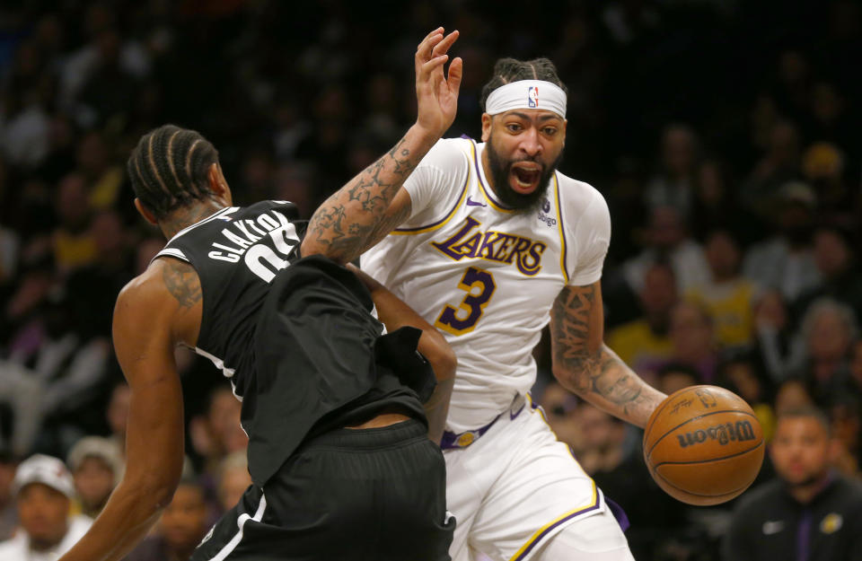 Los Angeles Lakers forward Anthony Davis, right, dribbles the ball around Brooklyn Nets center Nic Claxton during the first half of an NBA basketball game Sunday, March 31, 2024, in New York. (AP Photo/John Munson)