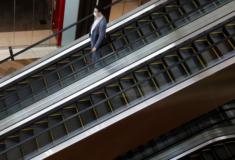 FILE PHOTO: A man wearing a mask takes the escalator, amid the coronavirus disease (COVID-19) outbreak in Singapore