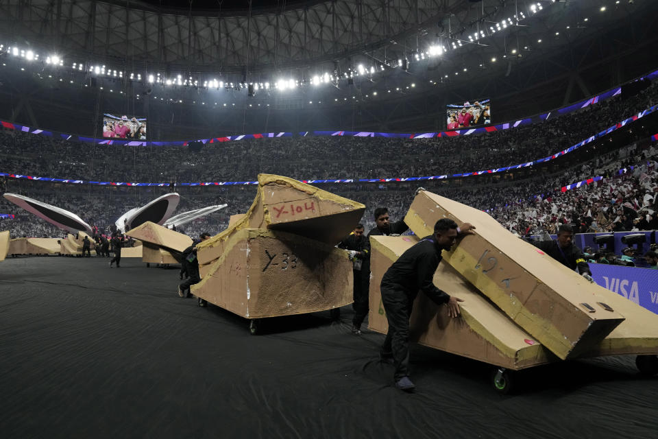 Migrant workers move away parts of the stage used during the opening ceremony ahead of the Asian Cup Group A soccer match between Qatar and Lebanon at Lusail Stadium in Lusail, Qatar, Friday, Jan. 12, 2024. The plight of migrant workers in Qatar came under the spotlight for more than decade after the gas-rich Middle Eastern emirate was awarded the World Cup in 2010. Workers labored in the searing heat to build over $200 billion worth of stadiums and infrastructure that helped make the tournament such a success. (AP Photo/Aijaz Rahi)