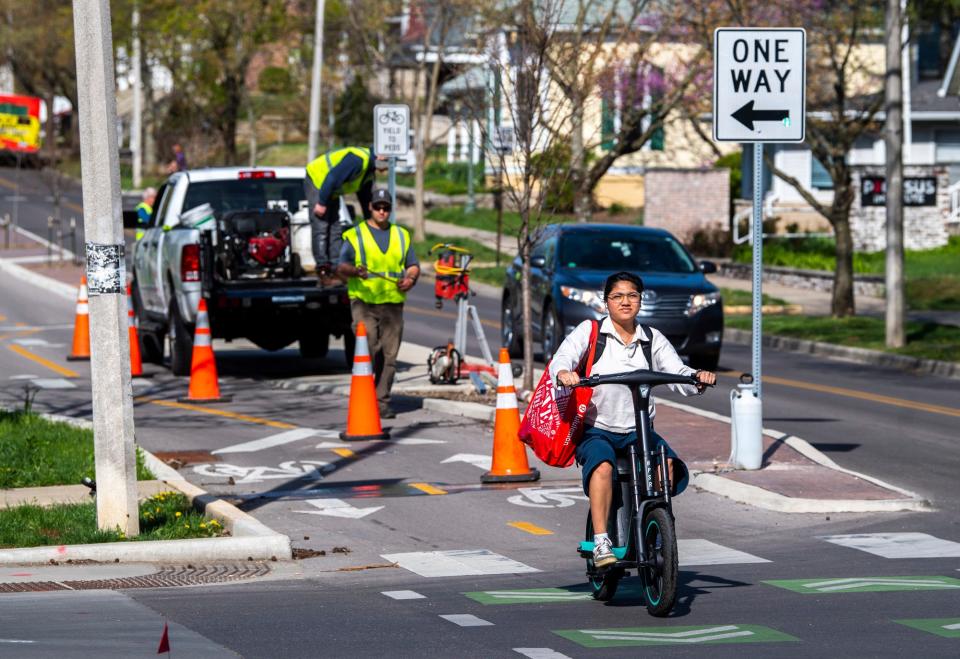 A person on a scooter rides through the intersection of Seventh and Dunn. The Bloomington City Council voted to reinstall stop signs at several intersections on Seventh Street, where a protected bike lane was constructed in 2021.