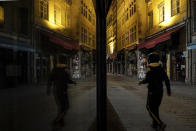 A man walks in the empty center of Lyon, central France, Saturday, Oct. 17, 2020. France is deploying 12,000 police officers to enforce a new curfew that came into effect Friday night for the next month to slow the virus spread, and will spend another 1 billion euros to help businesses hit by the new restrictions. (AP Photo/Laurent Cipriani)