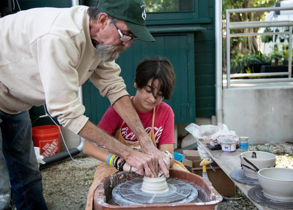 Everett Giles, right, gets help from Joseph Mayhew of JM Pottery while trying out Mayhew's pottery wheel at the Edison & Ford Winter Estates Garden Festival.
