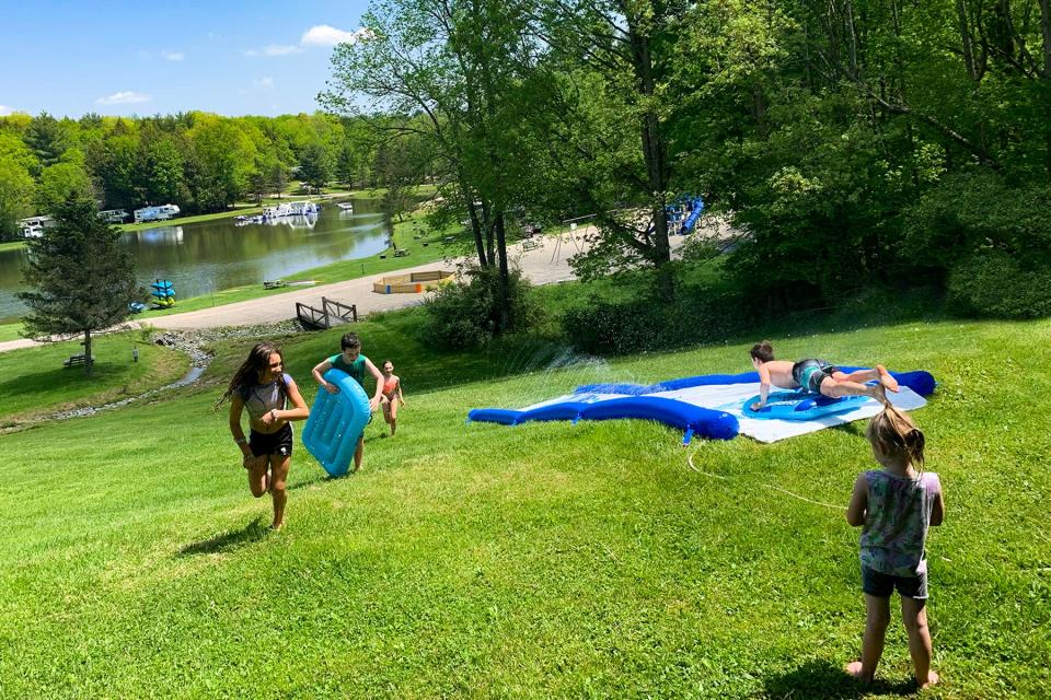 Young campers enjoy a slip-n-slide near the lake at the rebranded Binghamton Jellystone Park.