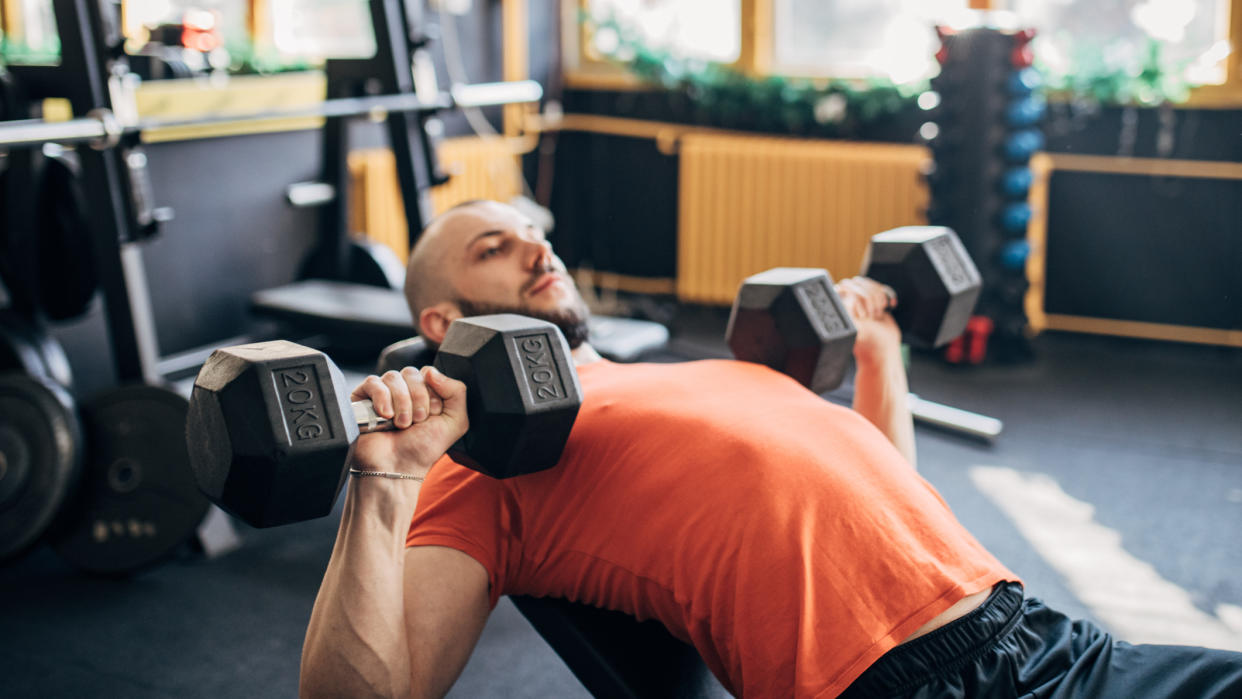  Man performing incline bench press with dumbbells. 