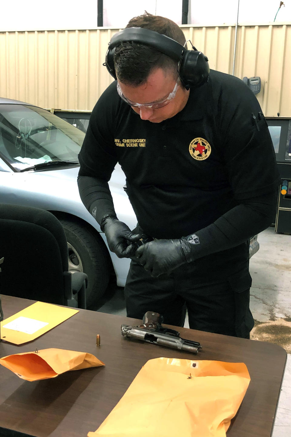 In this Monday, July 1, 2019 photo, Fort Bend County Sheriff's Office crime scene investigator David Chernosky prepares to test fire a handgun in Richmond, Texas, seized during a drug arrest so that another investigator can take the bullet casings and scan images of the casings and then upload them to a federal ballistics database. (AP Photo/Juan Lozano)