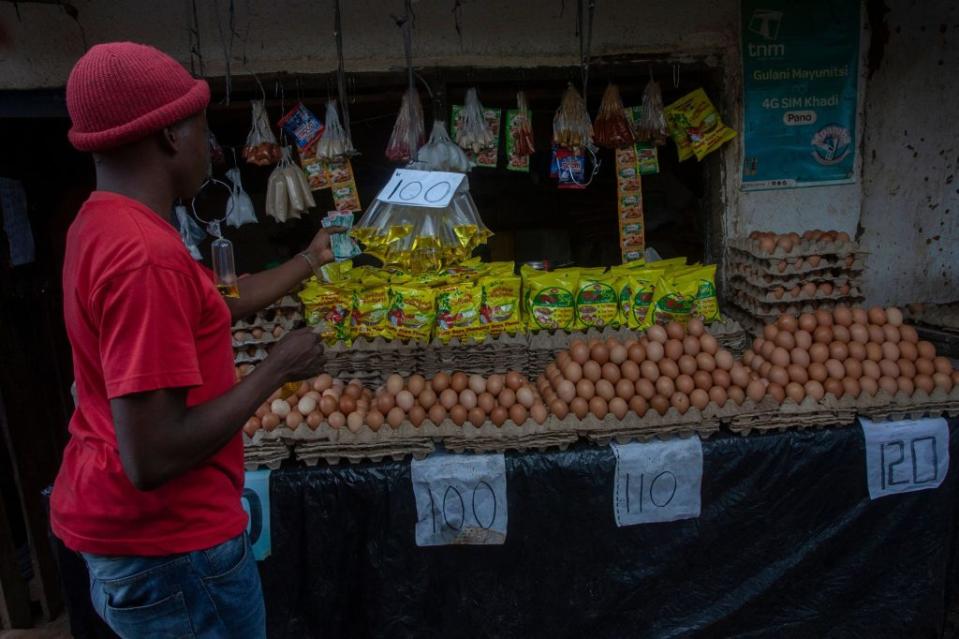 A man buys a sachet of cooking oil from an outdoor vendor in Lilongwe, Malawi, on March 16, 2022.