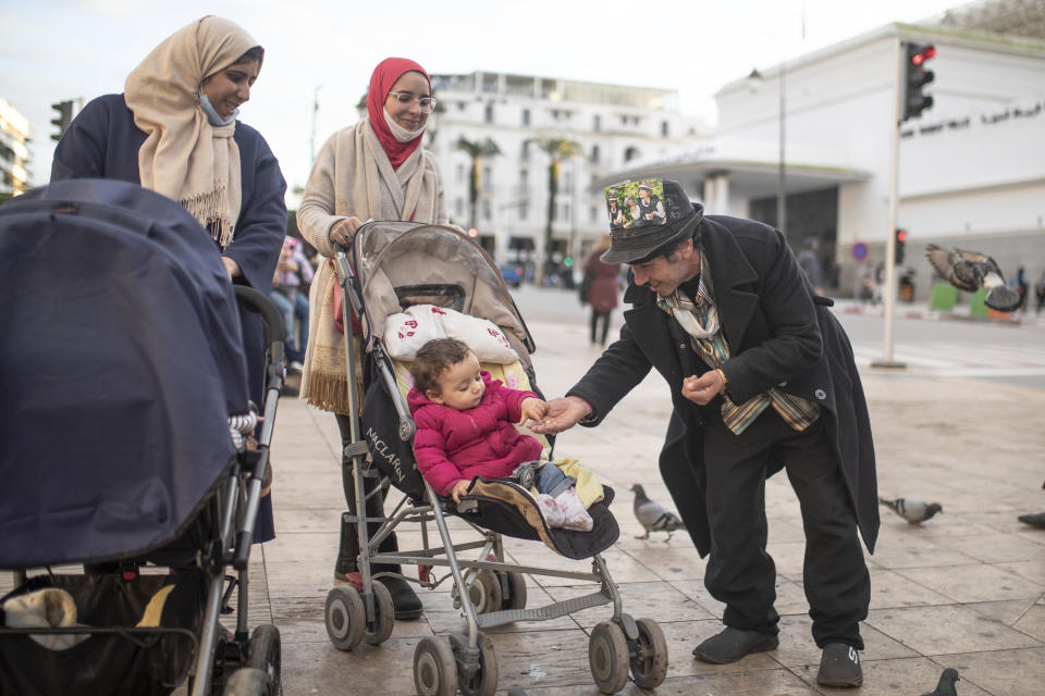 Belhussein Abdelsalam, a Charlie Chaplin impersonator reacts while performing for some children, in an avenue in Rabat, Morocco, Thursday, Dec. 17, 2020. When 58-year-old Moroccan Belhussein Abdelsalam was arrested and lost his job three decades ago, he saw Charlie Chaplin on television and in that moment decided upon a new career: impersonating the British actor and silent movie maker remembered for his Little Tramp character. (AP Photo/Mosa'ab Elshamy)