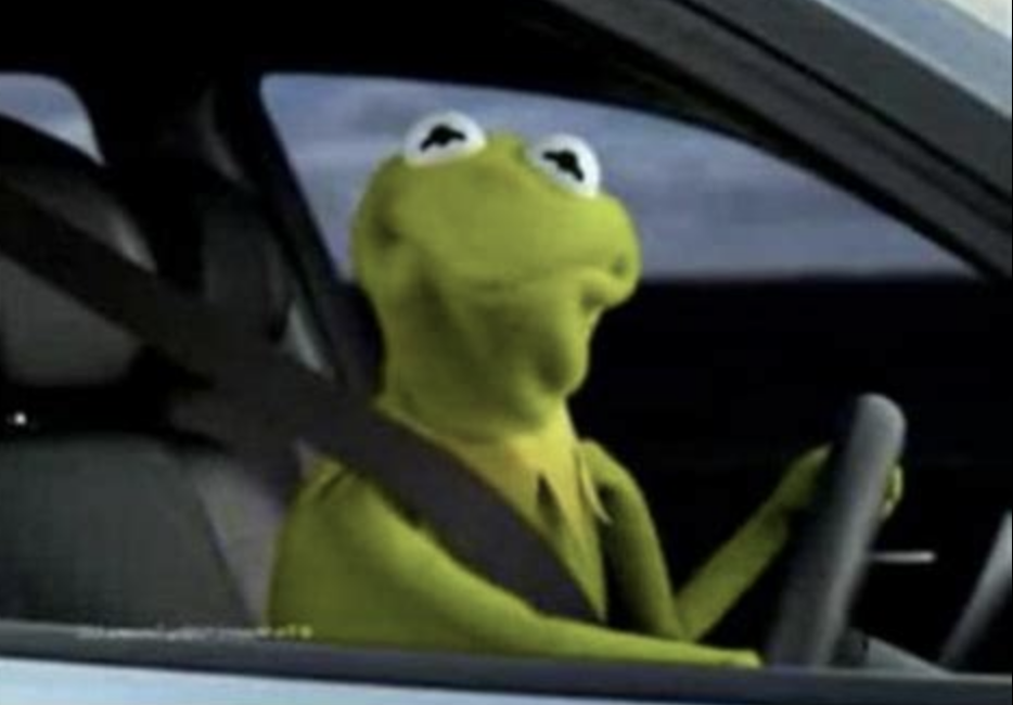 Kermit the frog sitting in the driver's seat and looking to his right
