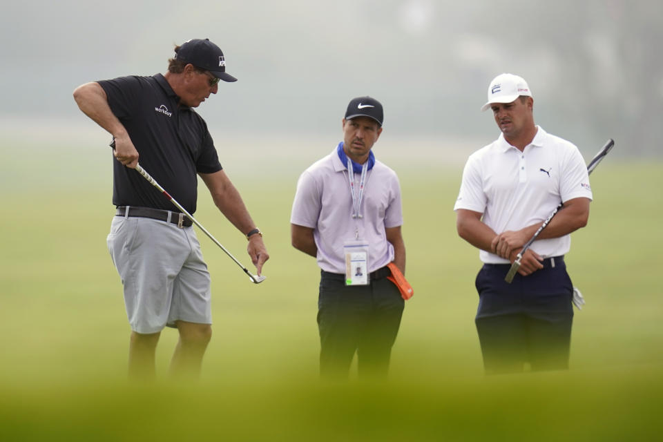 Phil Mickelson, left, talks with Bryson DeChambeau, right, and golf coach Chris Como, center, on the 12th hole during a practice round of the U.S. Open Golf Championship Monday, June 14, 2021, at Torrey Pines Golf Course in San Diego. (AP Photo/Gregory Bull)