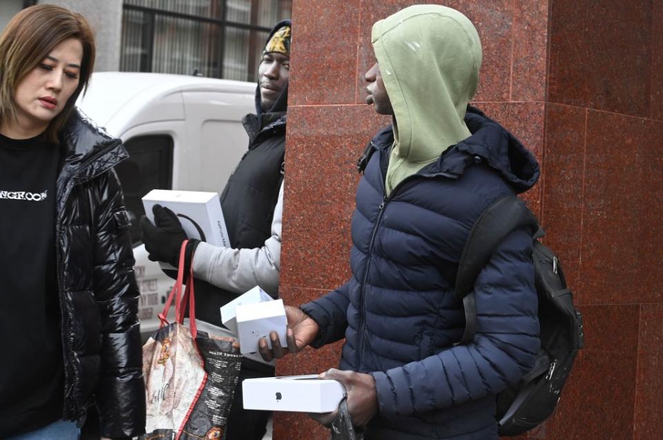 Two peddlers lay low while trying to sell bogus Apple merch to a pedestrian. Helayne Seidman