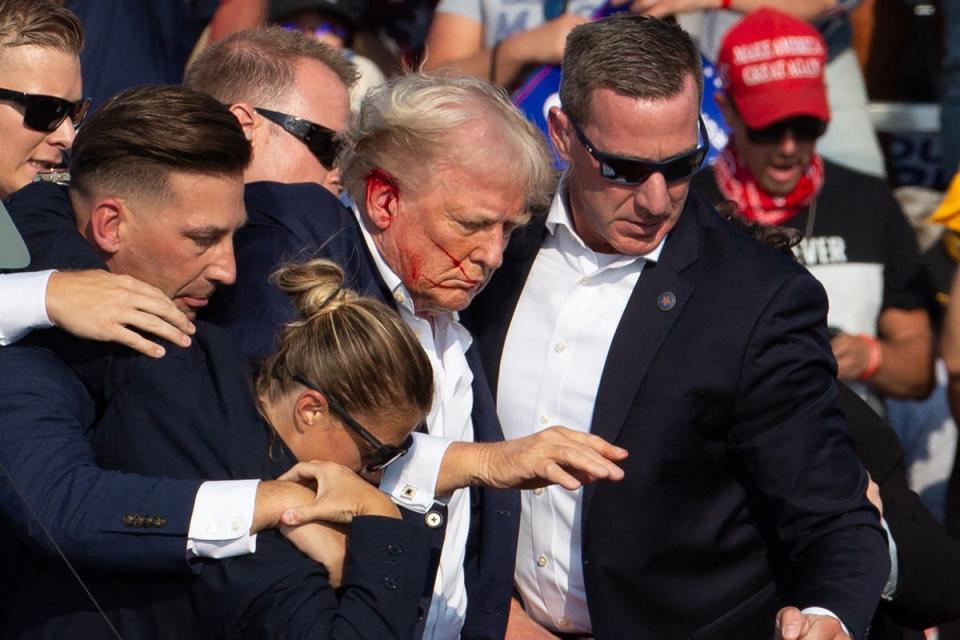 Donald Trump is seen with a blood-smeared face surrounded by Secret Service agents as he is led off the stage at a campaign rally in Butler, Pennsylvania, on July 13. Some Secret Service officials will now switch from Biden's to Trump's (AFP via Getty Images)