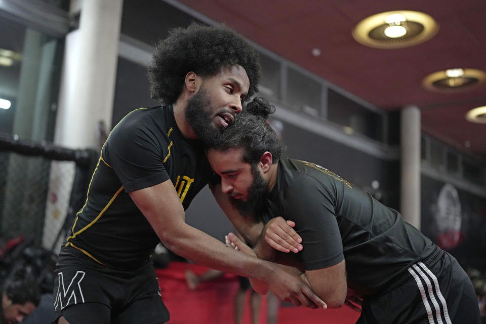 Flyweight MMA fighter Sabir Hussein, left, practices mixed martial arts moves with other student at Diesel Gym in the Docklands area of East London, Monday, March 25, 2024. The special sessions run by the nonprofit SCK Fitness are held at 10 p.m. during the Muslim holy month of Ramadan to accommodate dawn-to-dusk fasting. (AP Photo/Kin Cheung)