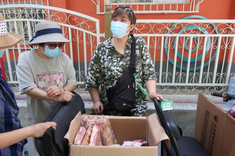 Street vendor Shan Peng attends to customers at her food stall set up on an electric tricycle outside a residential compound in Beijing