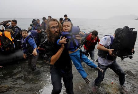 A volunteer carries a Syrian refugee child off an overcrowded dinghy at a beach after the migrants crossed part of the Aegean Sea from Turkey to the Greek island of Lesbos in this September 23, 2015 file photo. REUTERS/Yannis Behrakis/files