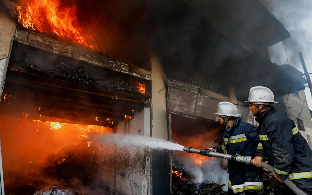 Palestinian firefighters try to extinguish a fire in a house after a reported air strike in Khan Younis in the southern Gaza Strip