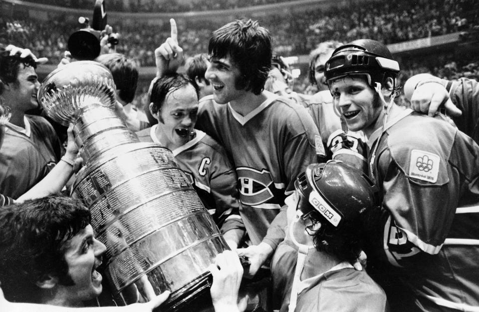 Yvan Cournoyer, captain of the Montreal Canadiens, holds the Stanley Cup as he is surrounded by teammates in Philadelphia, Pa., Sunday night, May 16, 1976.  Montreal beat the Philadelphia Flyers to take the final series of the cup.