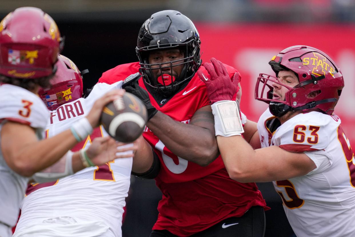 Oct 14, 2023; Cincinnati, Ohio, USA; Cincinnati Bearcats defensive end Jowon Briggs (middle) rushes from the line of scrimmage against Iowa State Cyclones defensive end David Caulker (left) and offensive lineman Jim Bonifas (right) in the second half at Nippert Stadium. Mandatory Credit: Aaron Doster-USA TODAY Sports