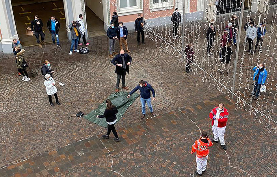 Rescue workers and onlookers stand near the scene after a car drove into a pedestrian zone in the city of Trier in Germany, Tuesday, Dec 1, 2020. German police say two people have been killed and several others injured in the southwestern German city of Trier when a car drove into a pedestrian zone. Trier police tweeted that the driver had been arrested and the vehicle impounded. (AP Photo/Sebastian Schmitz, lokalo.de)