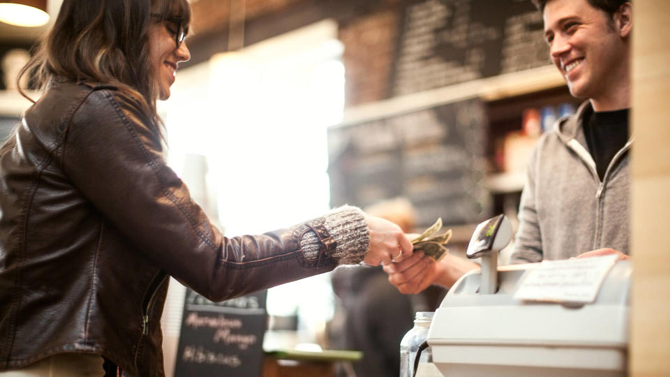 A woman is paying at a coffee shop.
