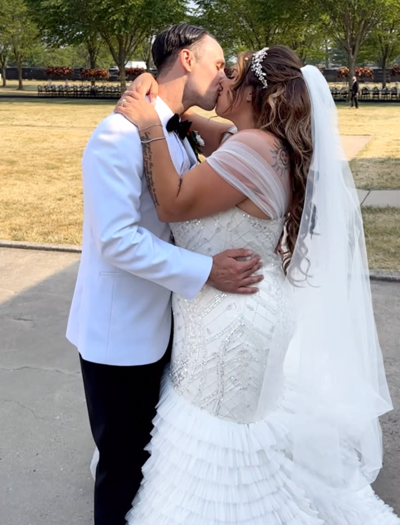 A bride and groom kiss in a park. (Alaina Scott / Instagram)