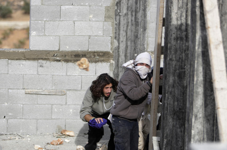 Palestinians throw stones at Israeli settlers near the West Bank village of Qusra,  Jan. 7, 2014. (AP Photo/Nasser Ishtayeh)