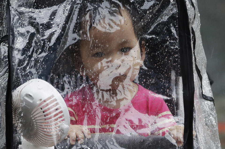 A baby looks out through the raindrop canopy in a rain caused by Typhoon Chanthu in Taipei, Taiwan, Sunday, Sept. 12, 2021. Typhoon Chanthu drenched Taiwan with heavy rain Sunday as the storm’s center passed the island’s east coast heading for Shanghai. (AP Photo/Chiang Ying-ying)