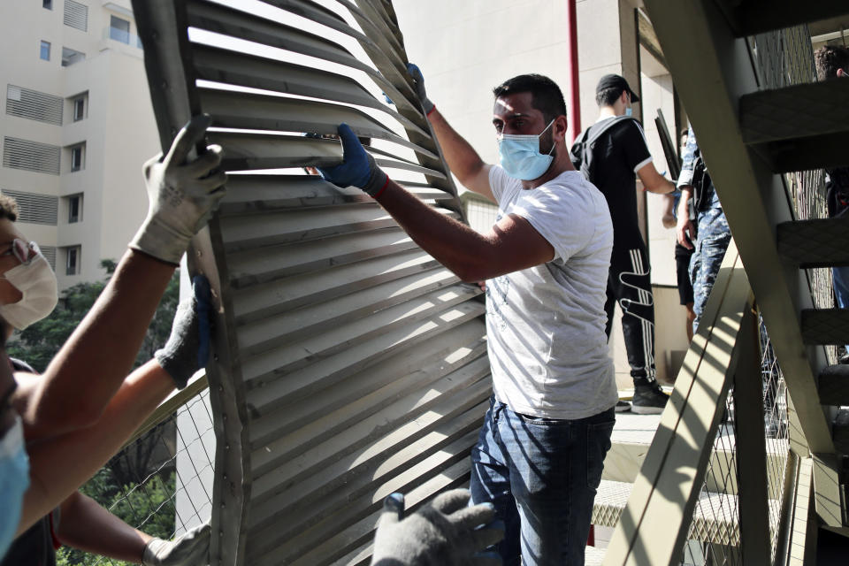 FILE - In this August 7, 2020 file photo, people remove debris from the damaged Rosary Sisters Hospital in a neighborhood near the scene of the Aug. 4 explosion that hit the seaport of Beirut, Lebanon. Eight hospitals and 20 clinics sustained partial or heavy structural damage and two hospitals remain largely out of service. The cost of repairs is estimated at nearly $30 million, the World Health Organization said. (AP Photo/Thibault Camus, File)