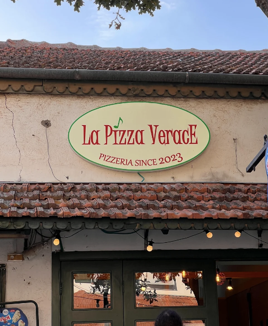 Sign for "La Pizza Verace," indicating a pizzeria established in 2023 with a terracotta roof above