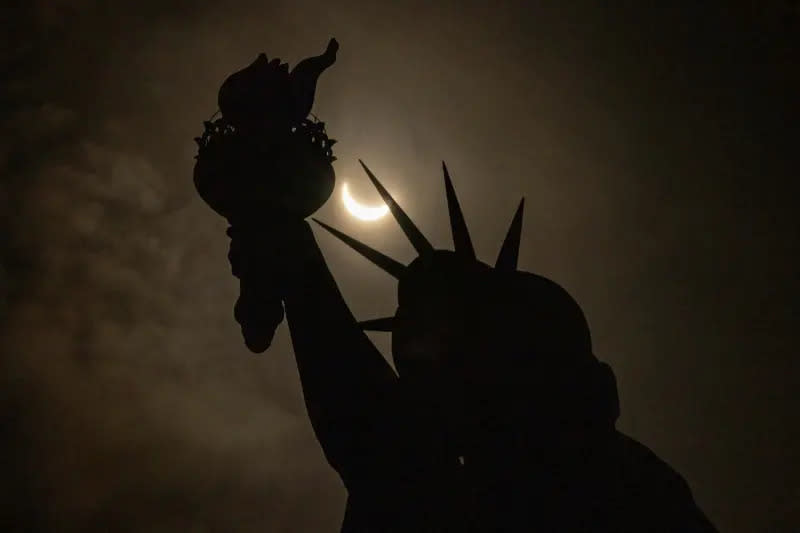 ▲知名的自由女神像上方，月亮逐漸遮住太陽的時刻。（圖／美聯社／達志影像）