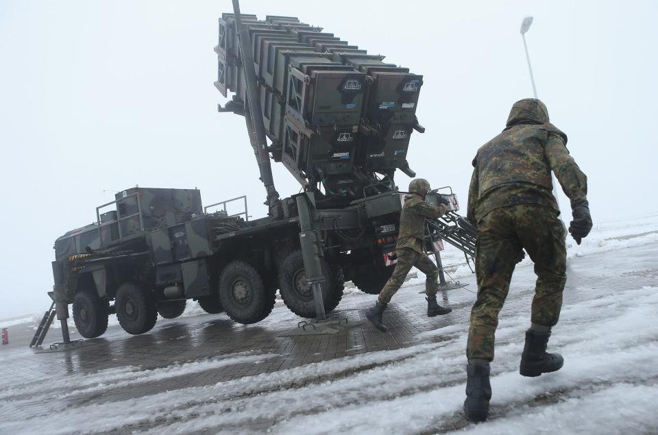 German soldiers prepare a Patriot missile launching system on snowy ground and against a grey sky