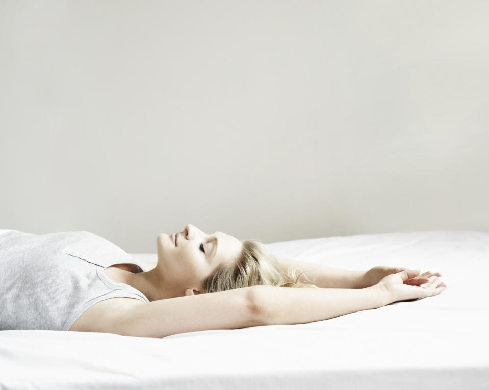 a woman lying on a bed with her arms up