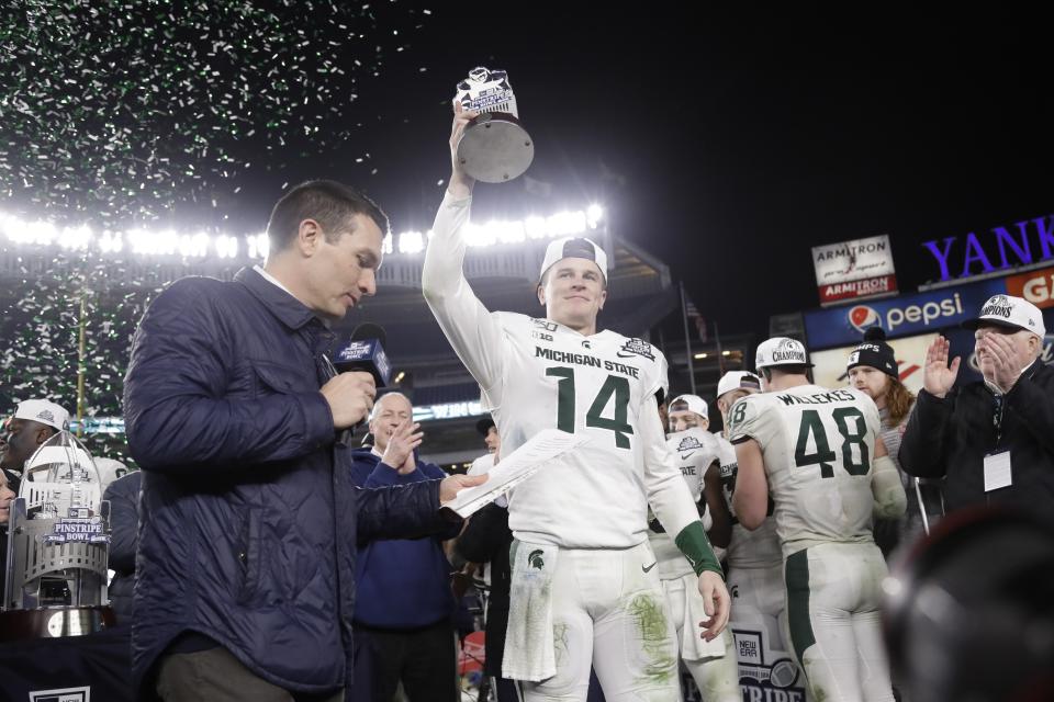 Michigan State's Brian Lewerke holds the Most Valuable Player trophy after the team's Pinstripe Bowl NCAA college football game against Wake Forest on Friday, Dec. 27, 2019, in New York. Michigan State won 27-21. (AP Photo/Frank Franklin II)