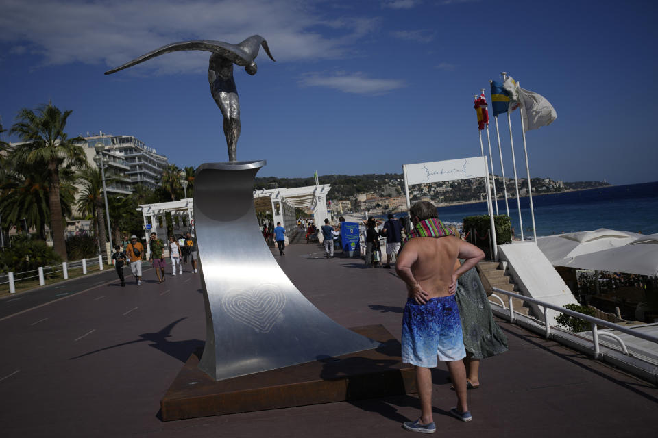 A couple stops along Nice's Promenade des Anglais to read the victims' names on "L'Ange de la Baie" statue created by Jean-Marie Fondacaro, to commemorate the 2016 terror attack, in Nice, South of France, Sunday, Sept. 4, 2022. Eight suspects will face trial in a Paris Court on Monday, in connection with the 2016 Bastille Day truck attack in Nice that left 86 people dead. (AP Photo/Daniel Cole)