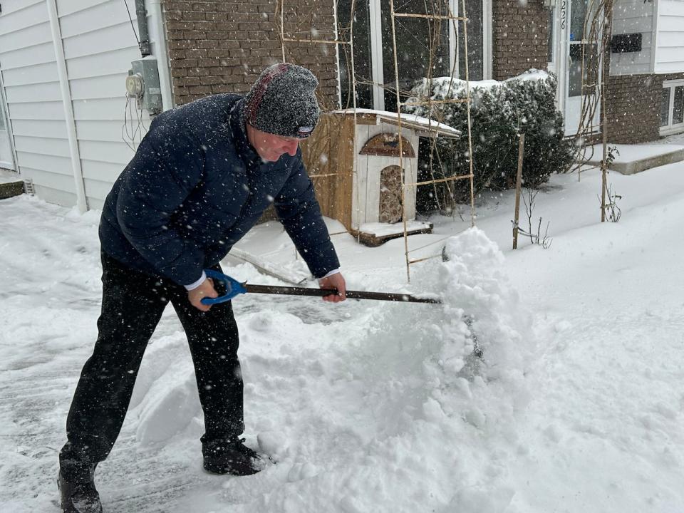 A man in Moncton shovels his driveway as snow continues to fall. 