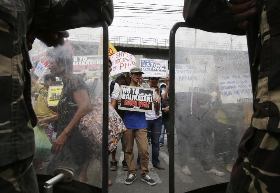 Protesters shout slogans as they picket the headquarters of the Armed Forces of the Philippines to coincide with the opening ceremony of the joint U.S.-Philippines military exercise dubbed Balikatan 2014, Monday, May 5, 2014 at suburban Quezon city, northeast of Manila, Philippines. More than 5,000 U.S. and Filipino troops have begun two weeks of military exercises to flex their muscle in jointly dealing with potential crisis in the Philippines, which is prone to natural disasters and has been locked in a dangerous standoff with China over a disputed shoal. This year's war games focuses on maritime security. (AP Photo/Bullit Marquez)