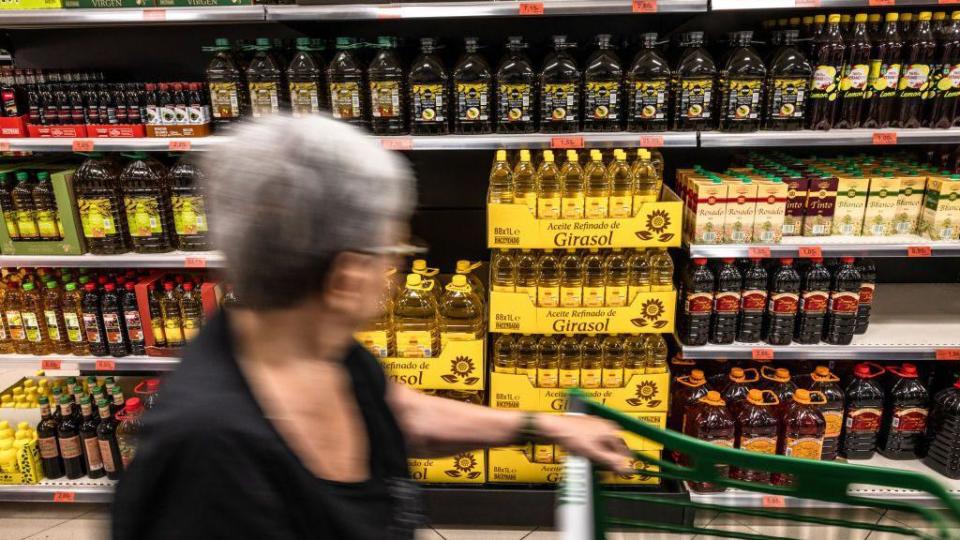 Señora en el pasillo del supermercado donde están los aceites